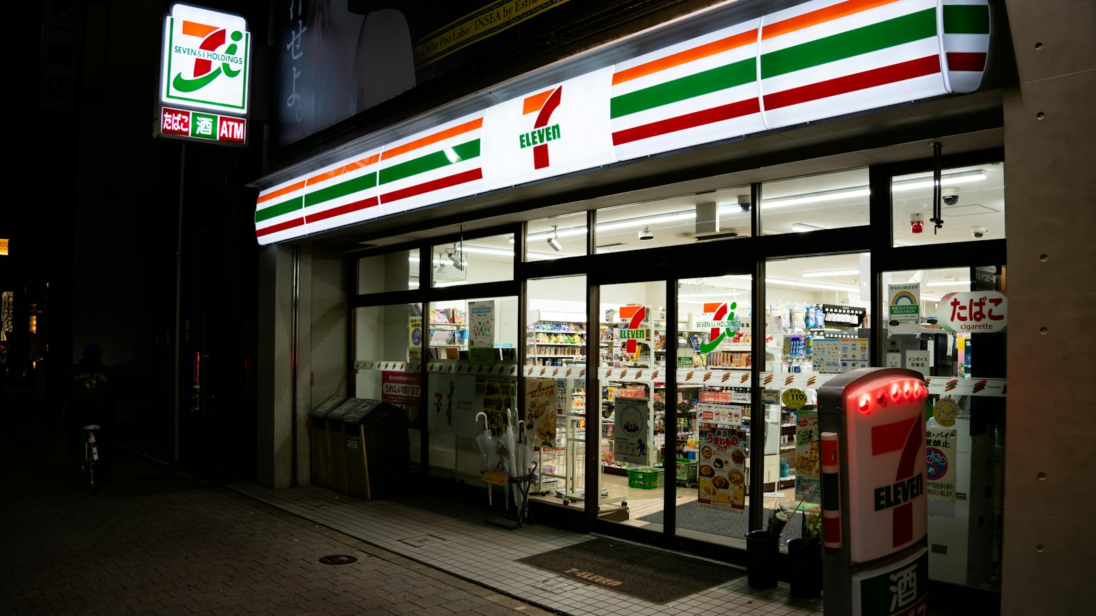 A brightly lit 7-Eleven storefront in Japan at night