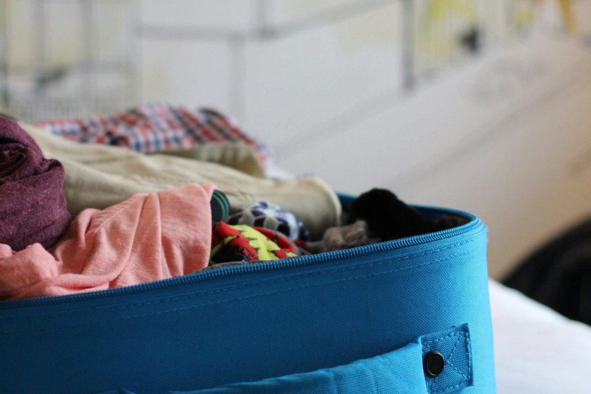 Blue soft-sided luggage filled with clothes, ready for packing