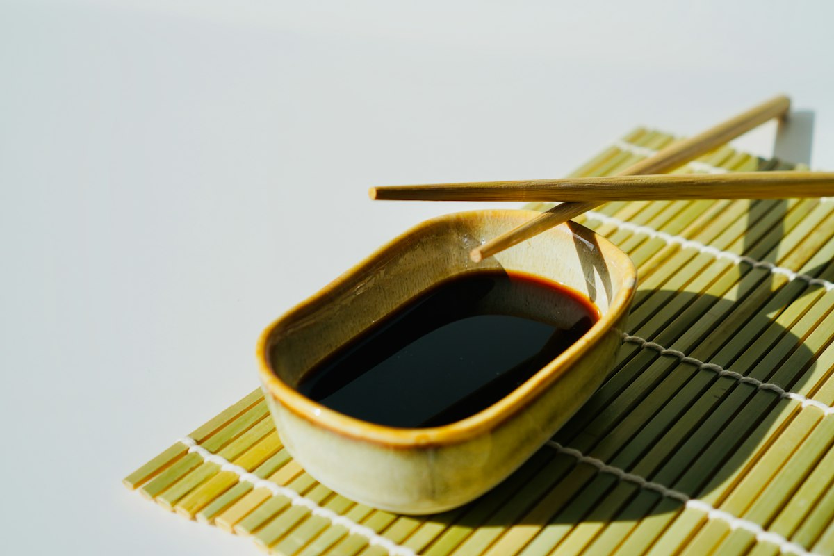 Chopsticks resting on a soy sauce dish over a bamboo mat