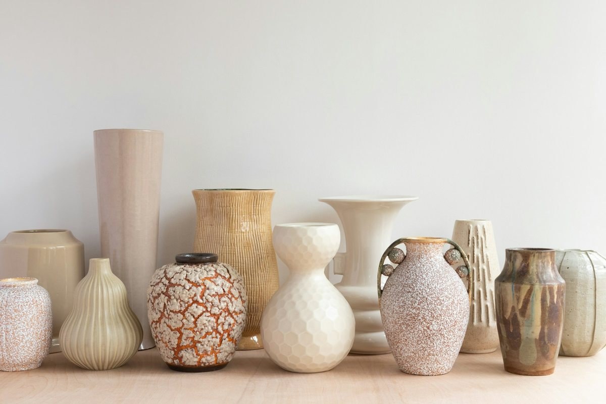 Collection of ceramic vases in neutral tones on a wooden shelf