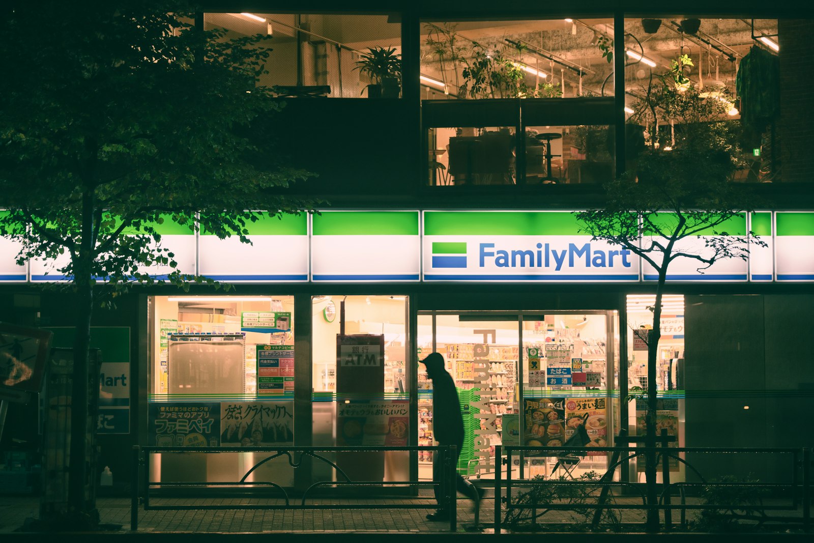 People walking past a FamilyMart convenience store at night