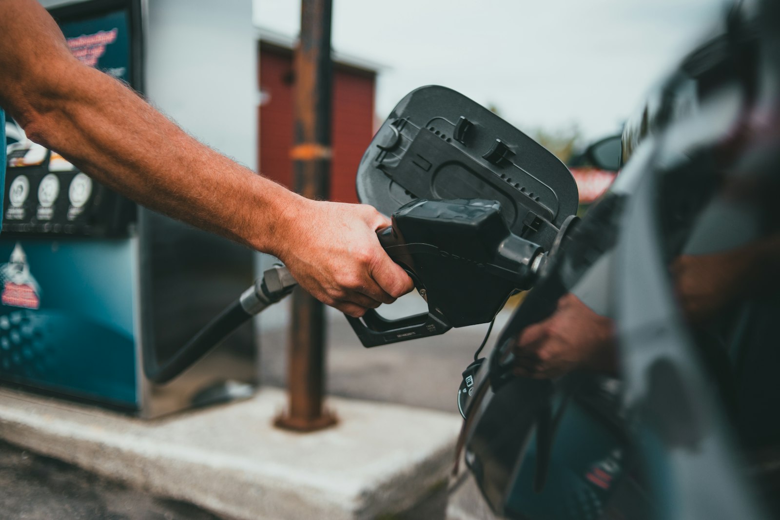 Hand holding a fuel nozzle to fill up a car