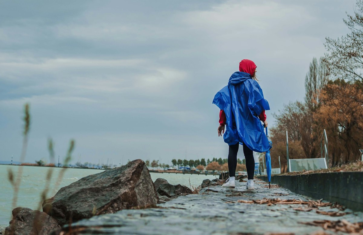 Person wearing a blue rain poncho standing on a rocky coast