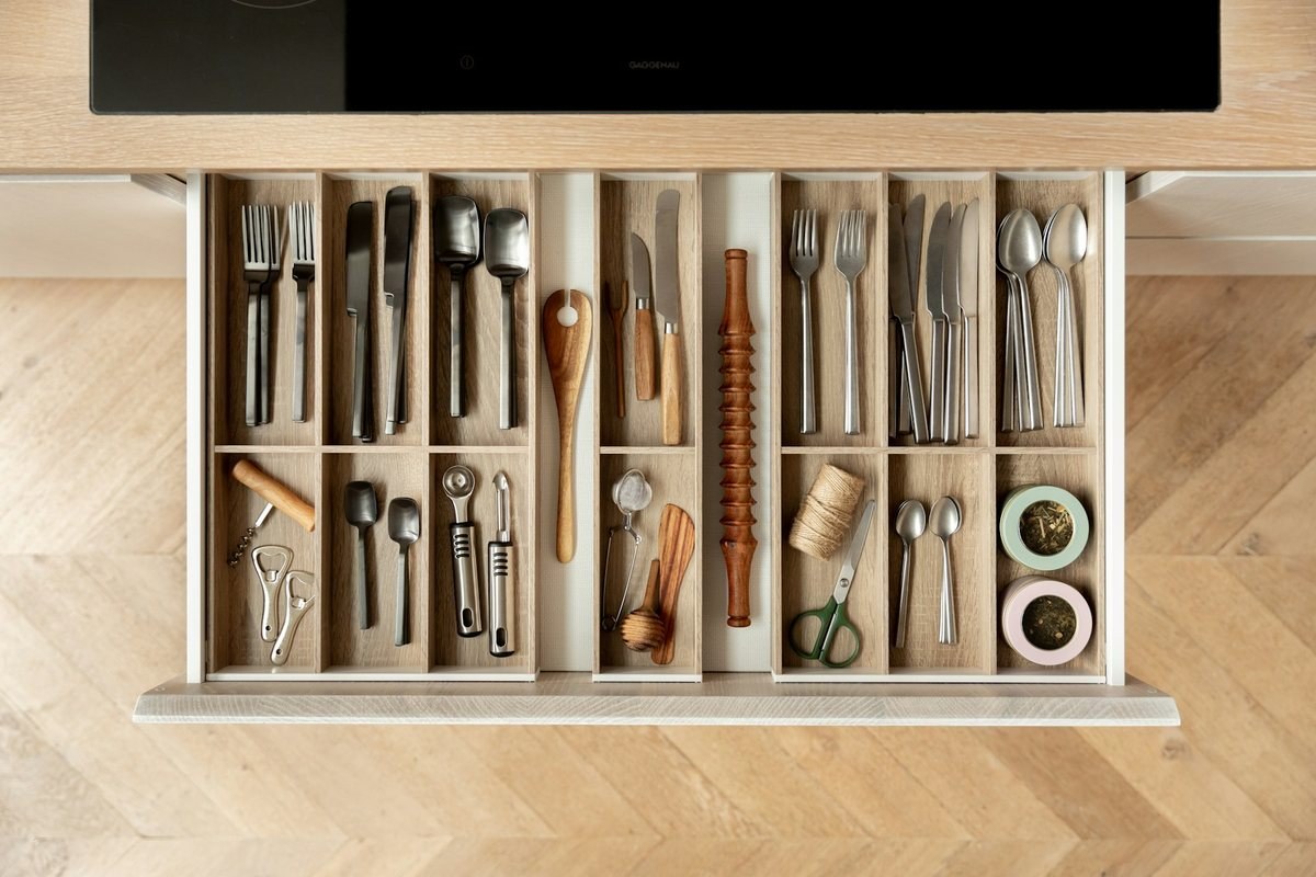 Kitchen drawer with wooden dividers holding cutlery and utensils
