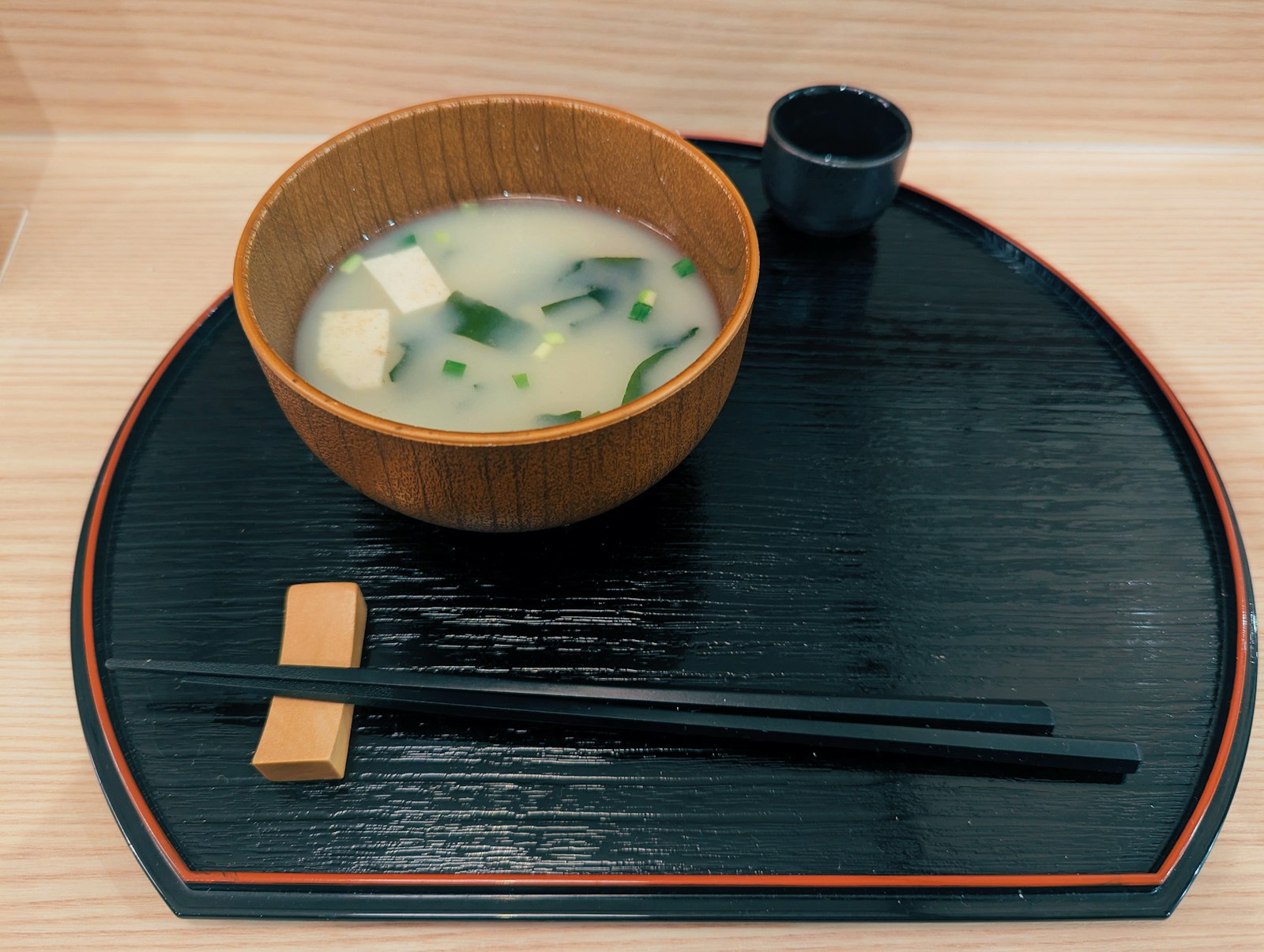 Bowl of miso soup on a dark lacquer tray with chopsticks