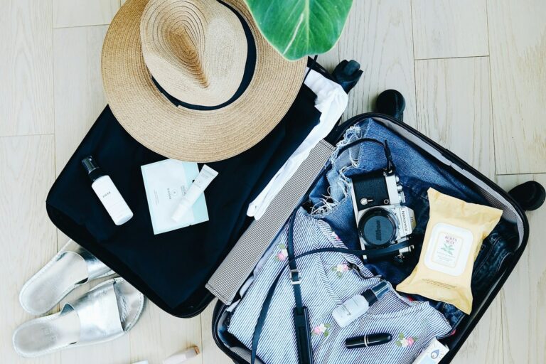 Open suitcase packed with a straw hat, clothes and travel essentials for a Japan trip