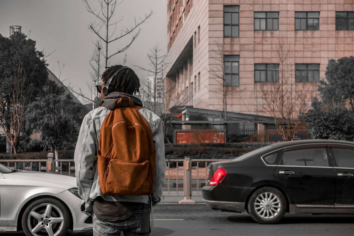 Person carrying an orange backpack on a city street