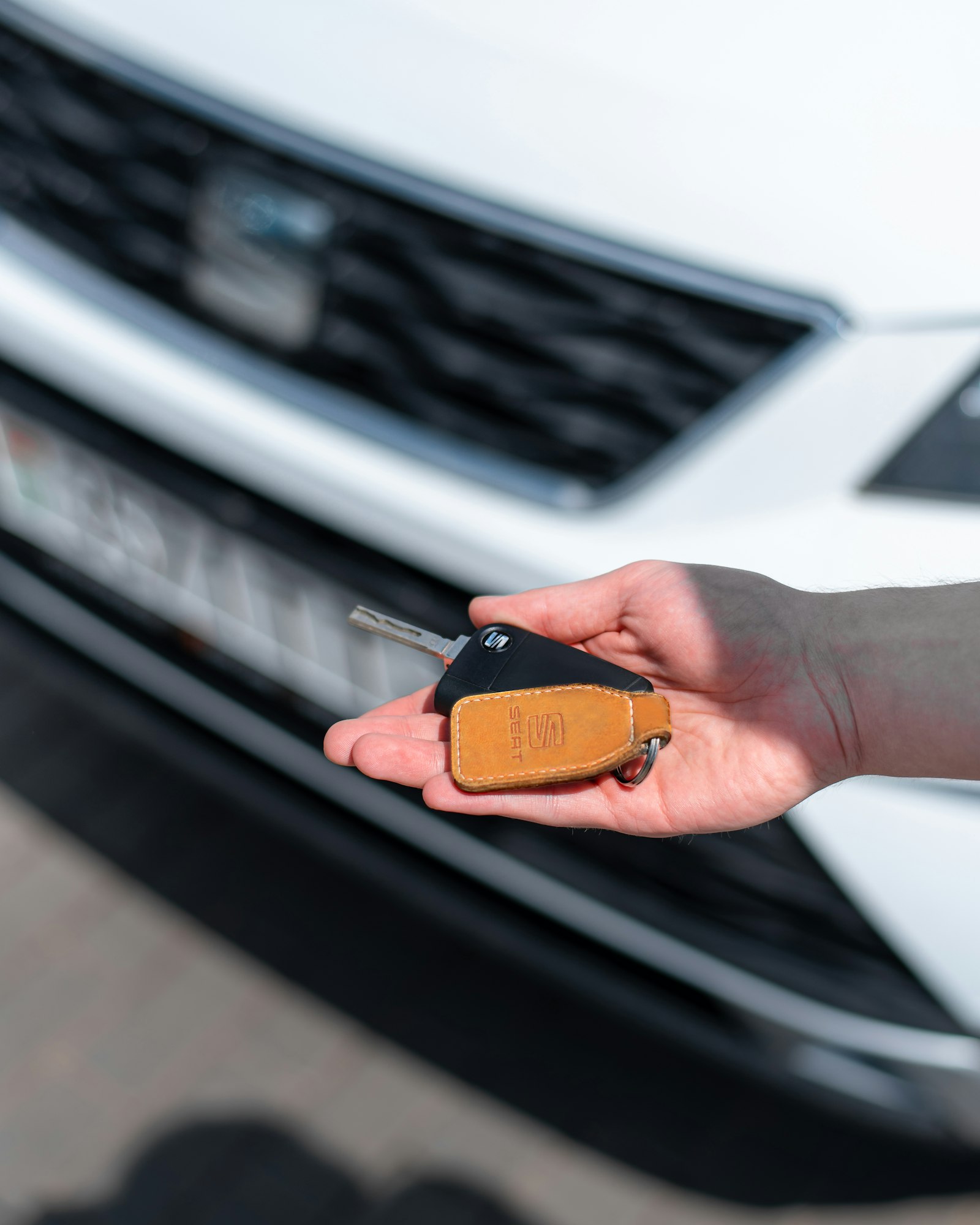 Hand holding a car key next to a car