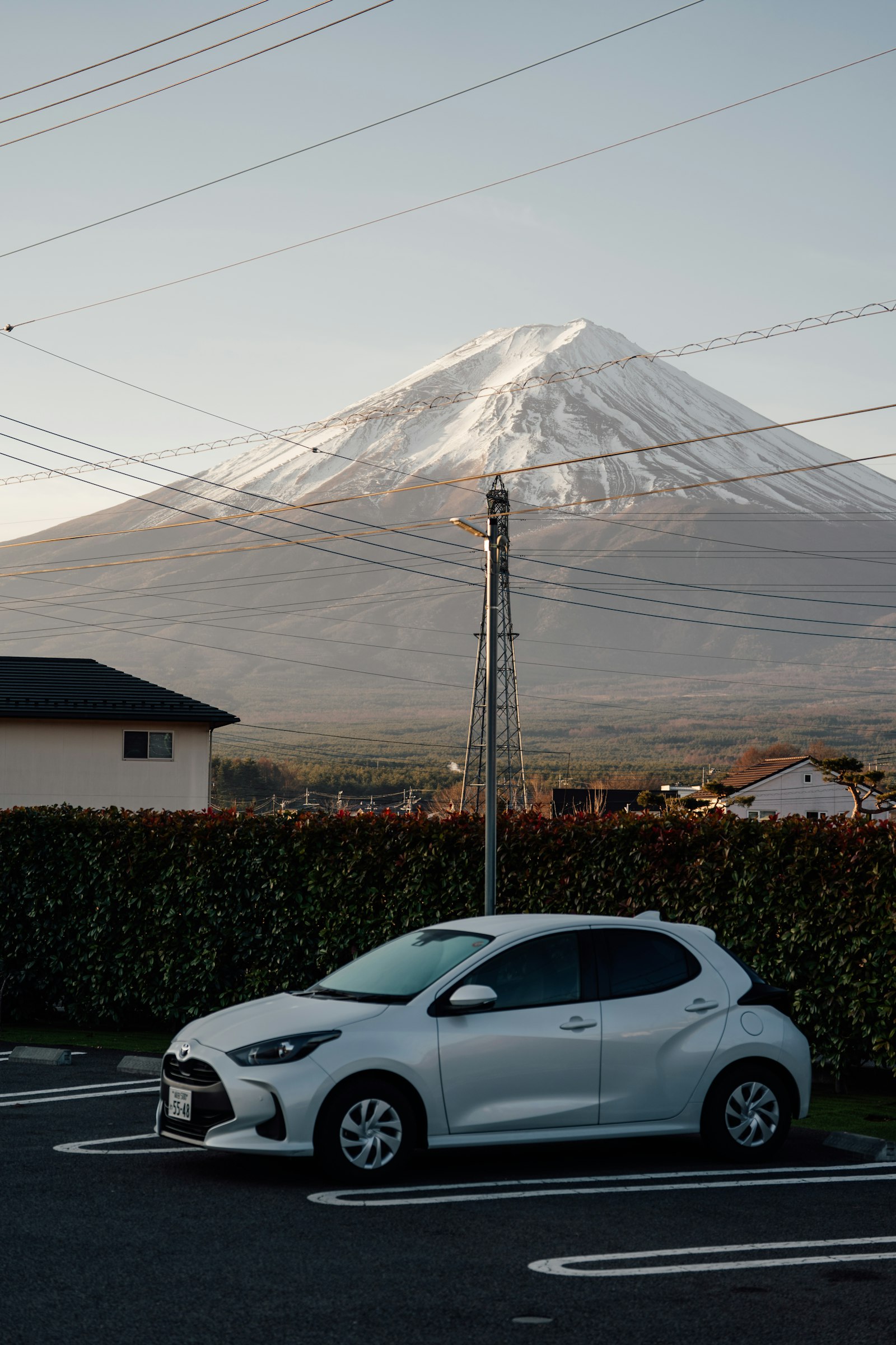 Car parked on a road with snow-capped Mount Fuji behind it