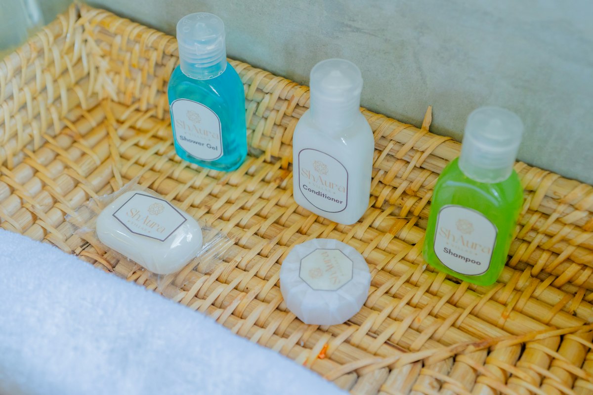 Small shampoo and soap bottles on a woven bathroom tray