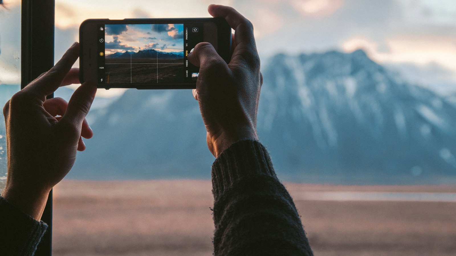 Hands taking a smartphone photo of a mountain view