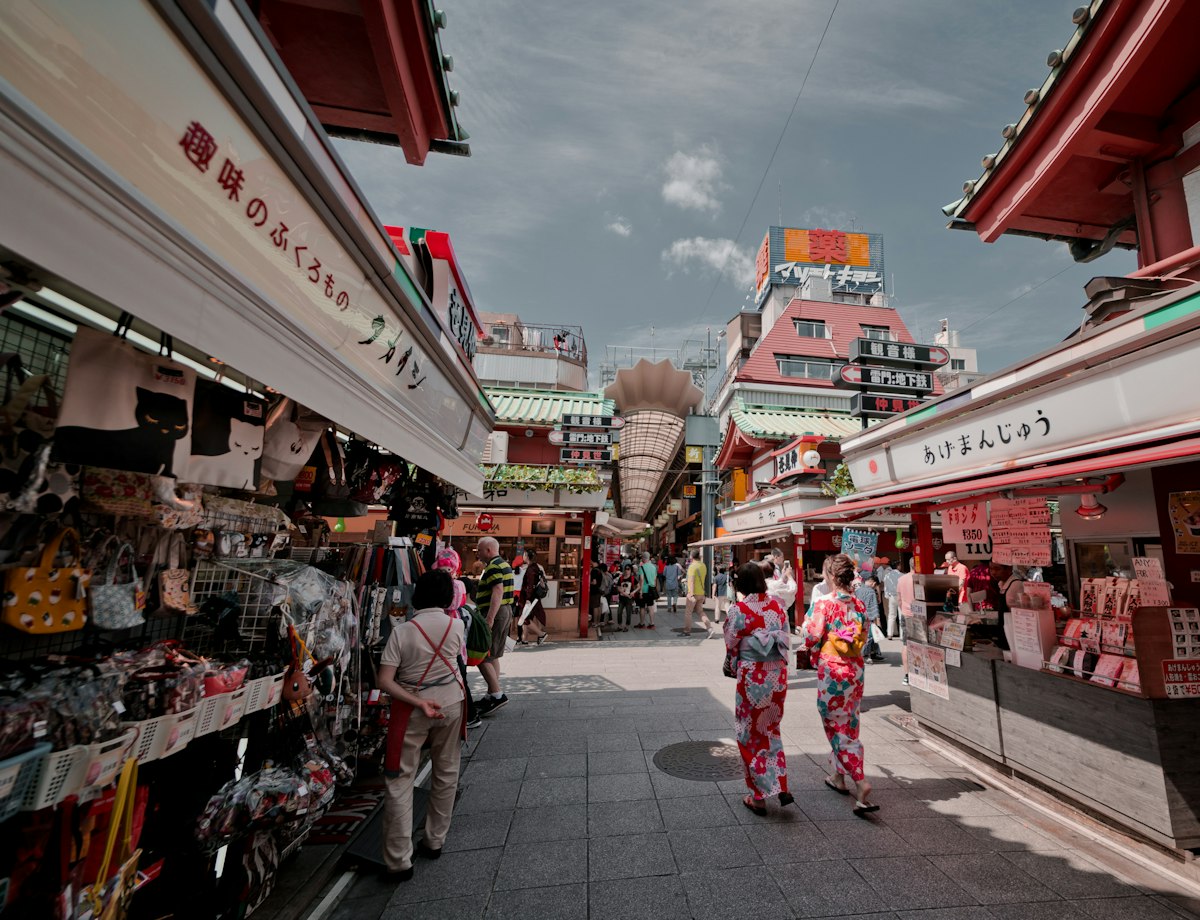 Sunny shopping street with shops and visitors in Japan