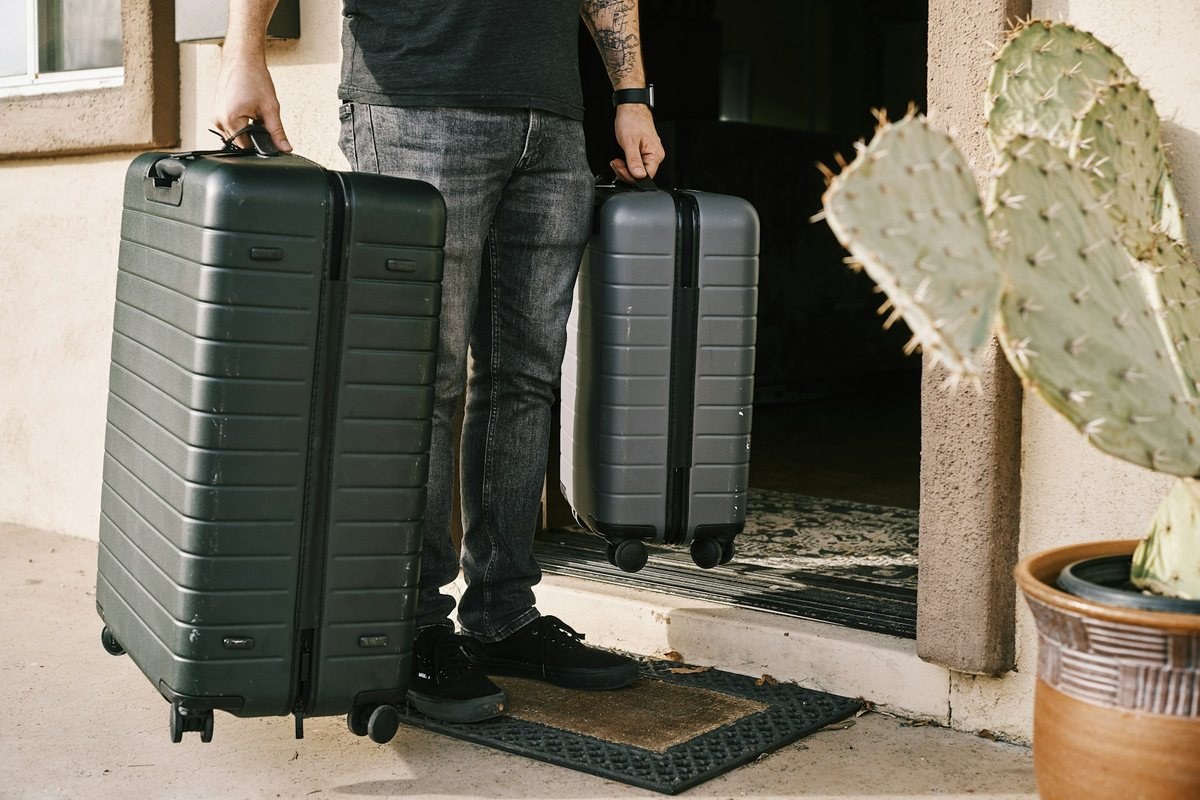 Two suitcases being carried through a doorway