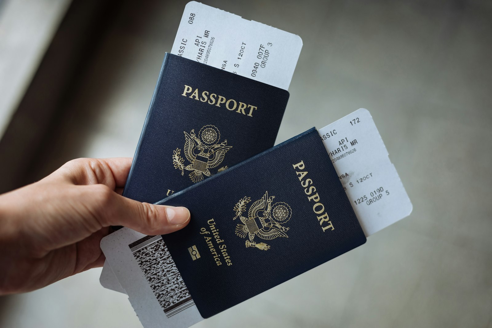 Two US passports with boarding passes held in a hand