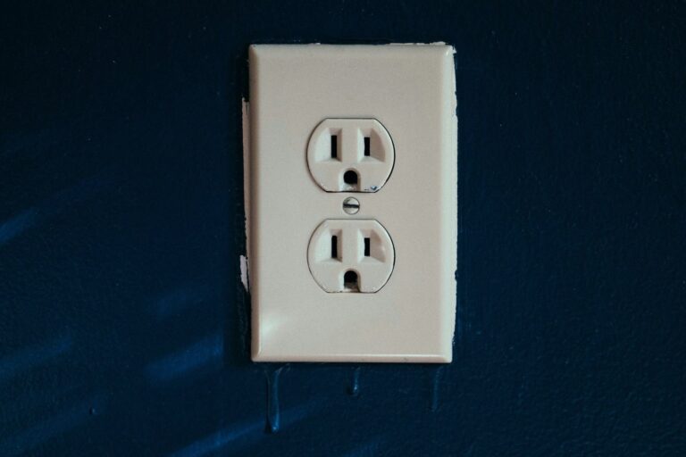 White electrical outlet with three-prong sockets on a navy blue wall