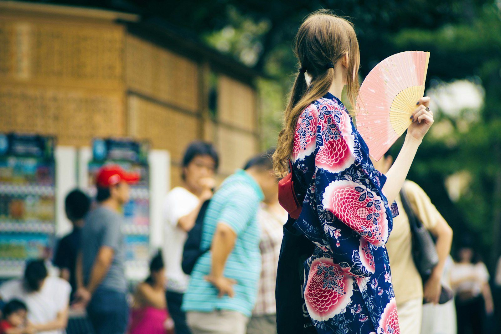 Woman in a yukata holding a paper fan on a summer street in Japan