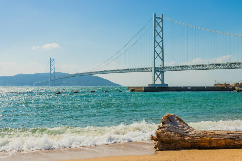 The Akashi Kaikyo Bridge spanning the Akashi Strait seen from a sandy beach