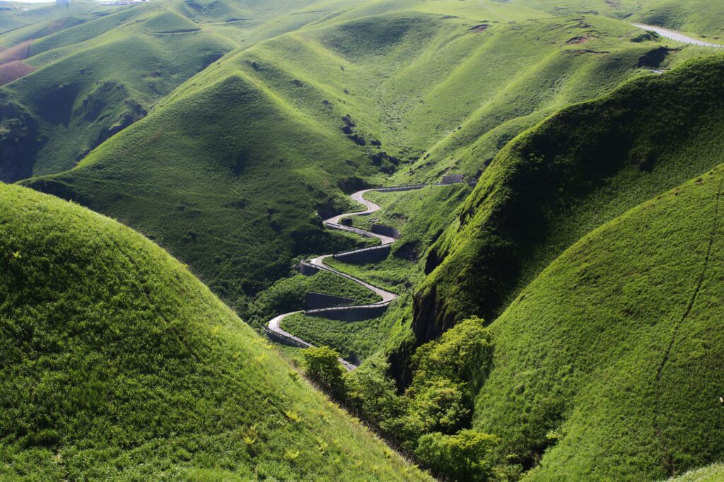 A road winding through the green ridges of Mount Aso