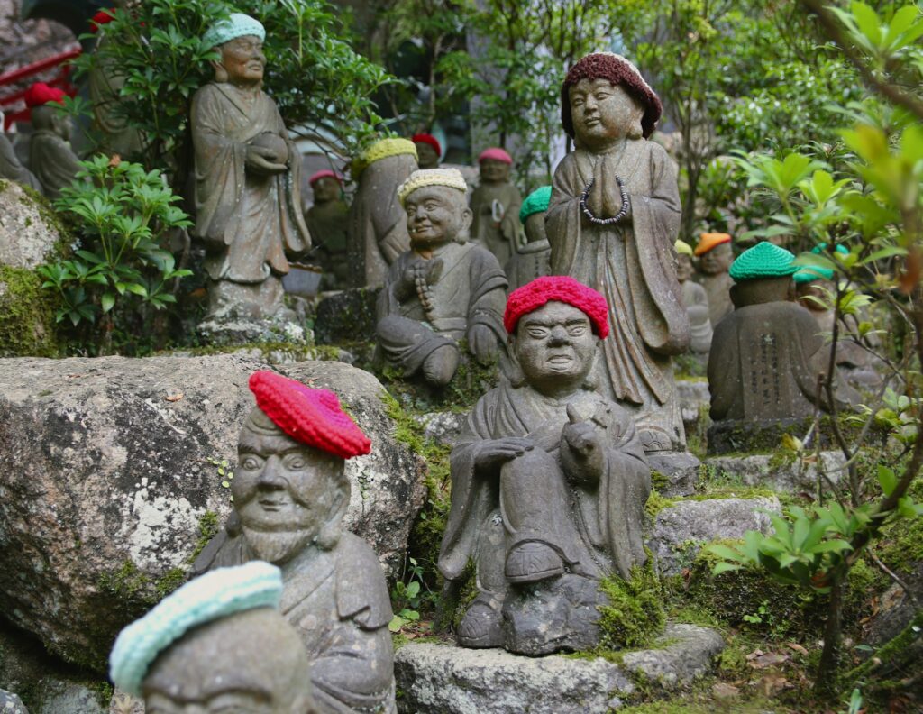 Stone rakan statues wearing knitted caps at Daisho-in Temple on Miyajima