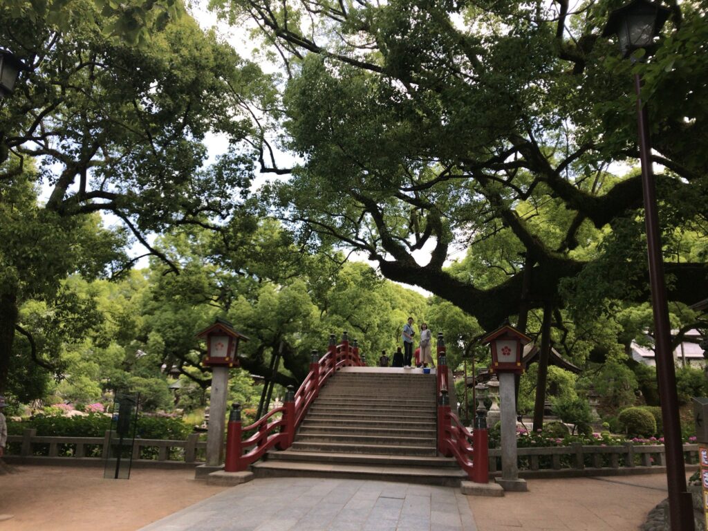 Red arched bridge and stone steps among the trees at Dazaifu Tenmangu Shrine