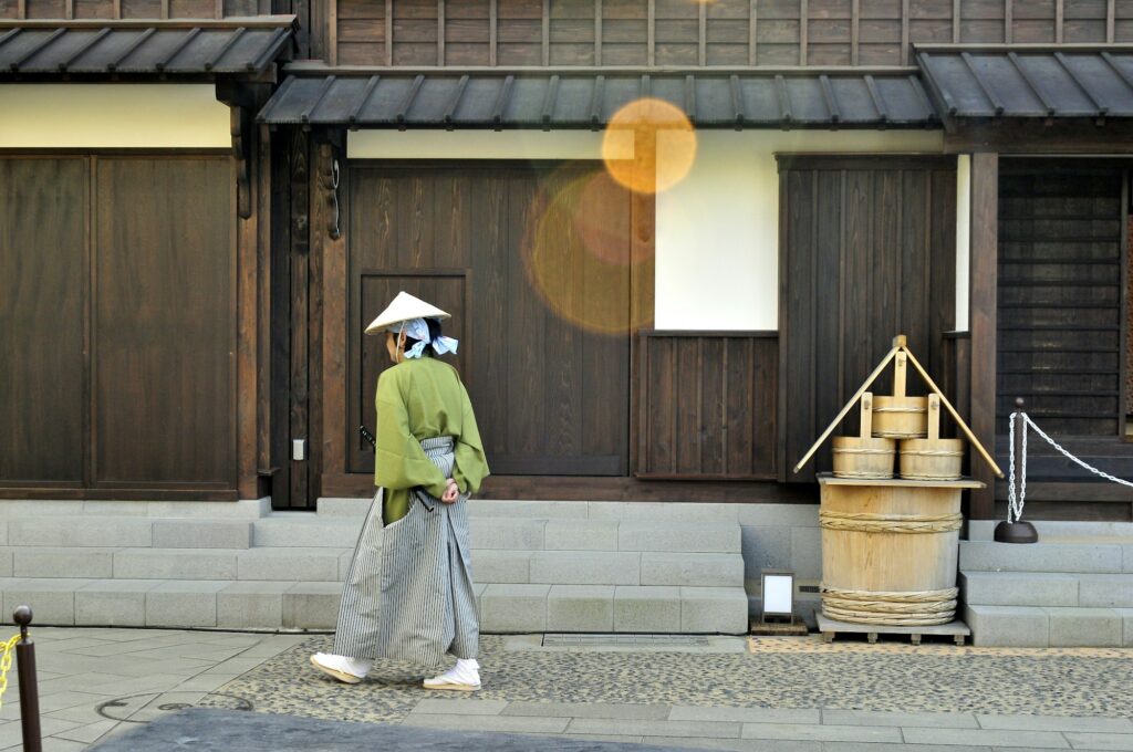 A costumed guide walking past restored wooden buildings on Dejima