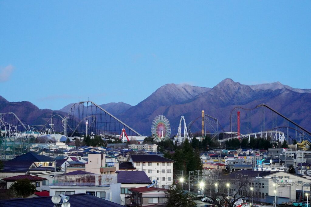 Roller coasters and the Ferris wheel of Fuji-Q Highland amusement park in Fujiyoshida with mountains behind