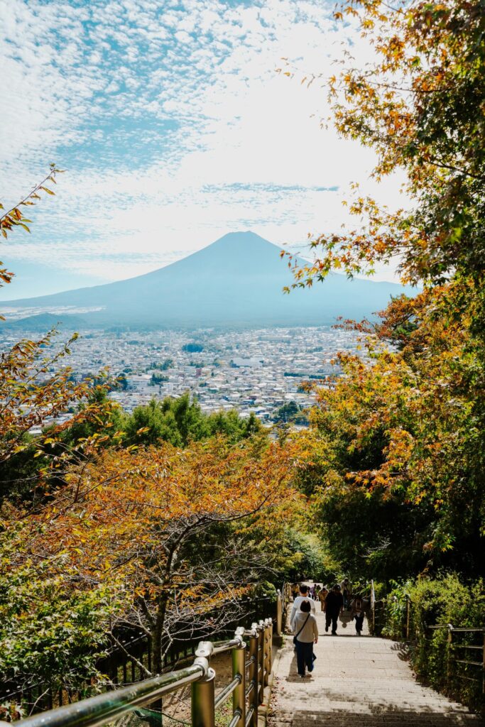 Fujiyoshida town spread out below Mount Fuji framed by autumn trees
