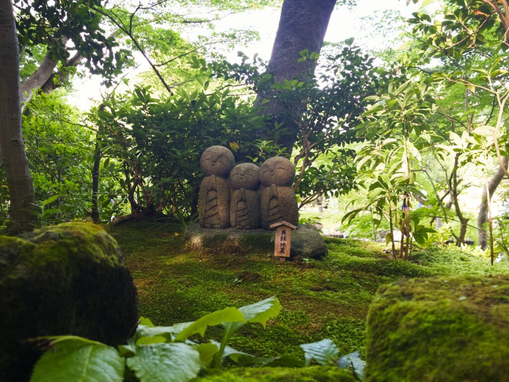 Small stone Jizo statues among moss and trees at Hasedera Temple in Kamakura
