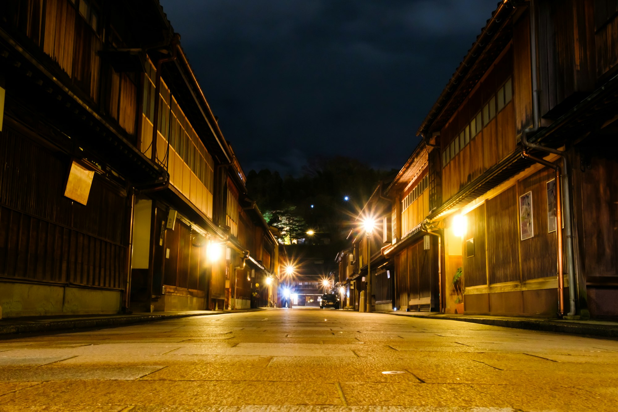Wooden teahouses lining a lamp-lit street in the Higashi Chaya District at night