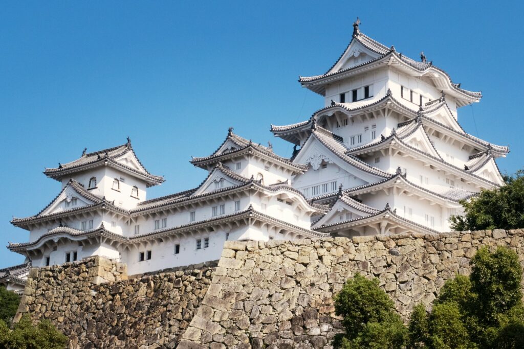 The white main keep and turrets of Himeji Castle above its stone walls