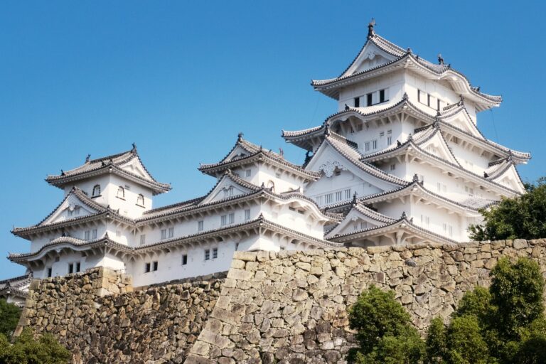 The white main keep and turrets of Himeji Castle above its stone walls