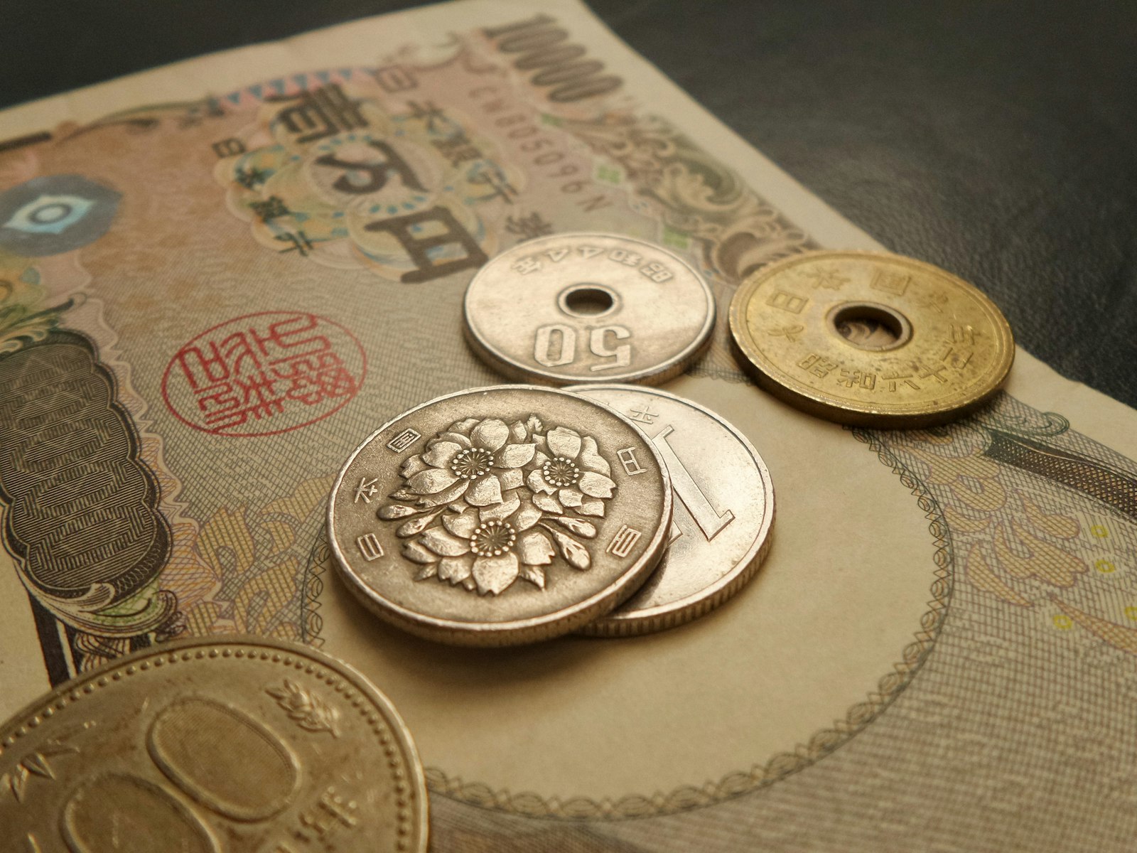 Japanese 500, 100, 50 and 5 yen coins resting on a yen banknote