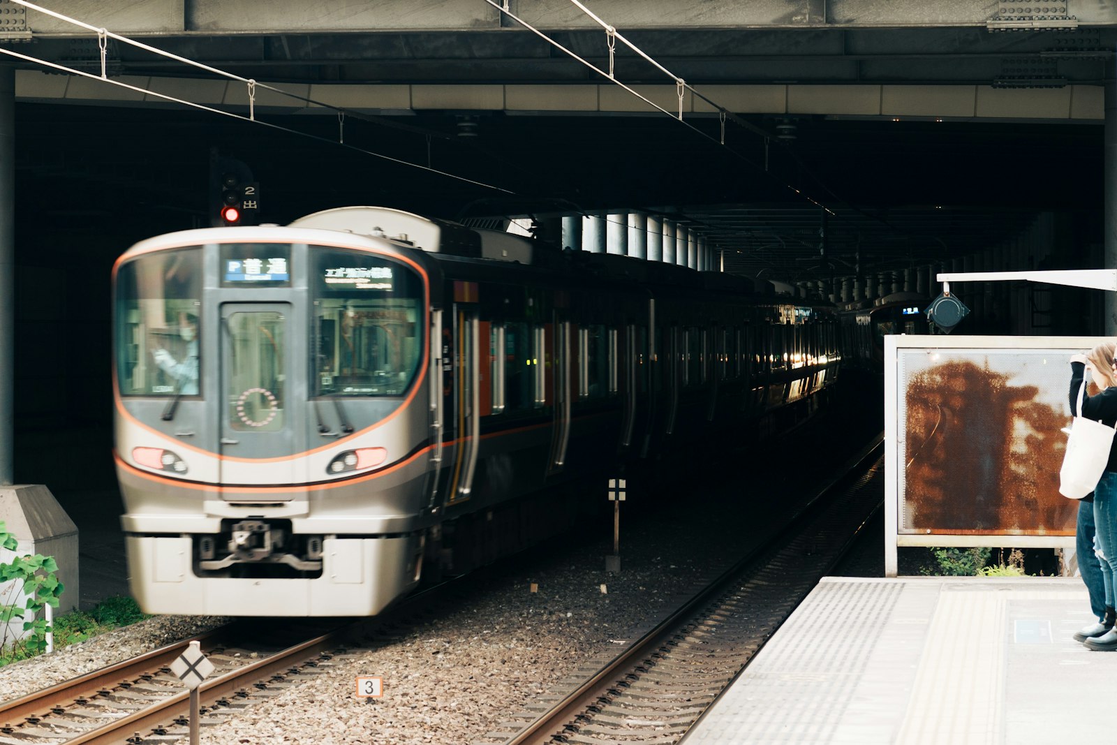 Silver and orange JR West commuter train waiting at a platform in Osaka