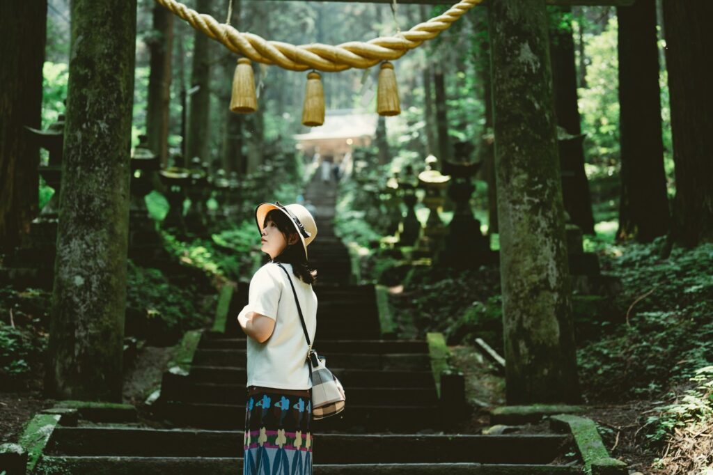 A visitor at a torii gate in the cedar forest of Kamishikimi Kumanoimasu Shrine