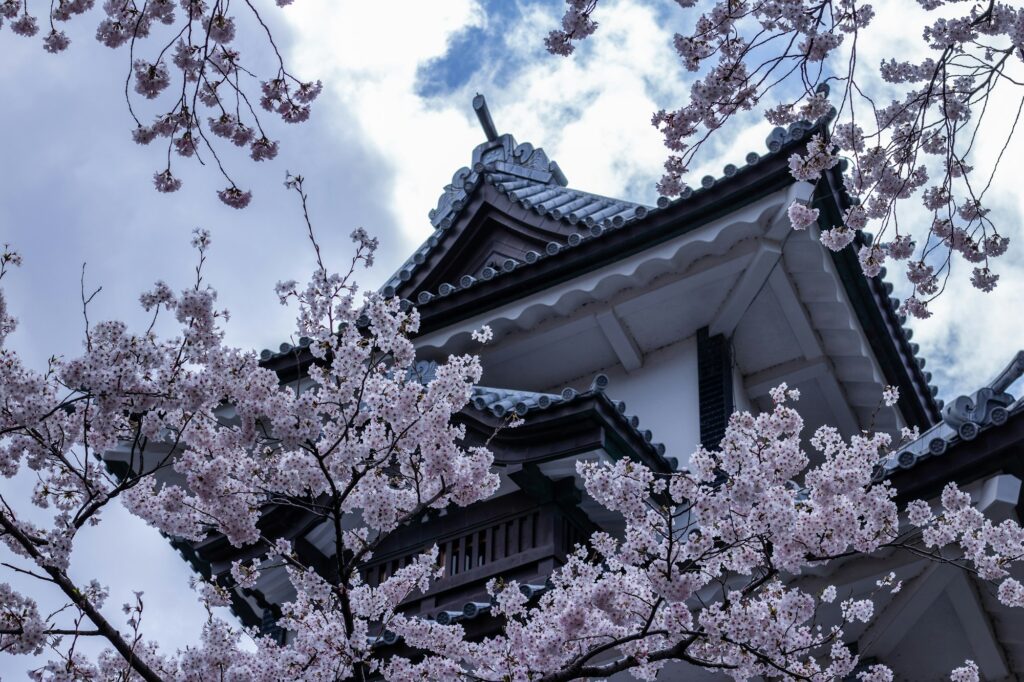 White walls and turrets of Kanazawa Castle above a stone-walled moat