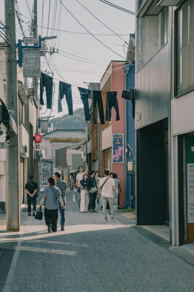 Shoppers walking along Kojima Jeans Street under hanging jeans