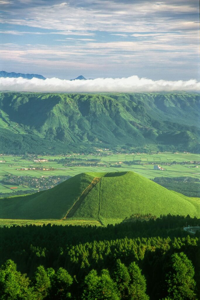 The small green volcanic cone of Komezuka rising from the Aso grasslands