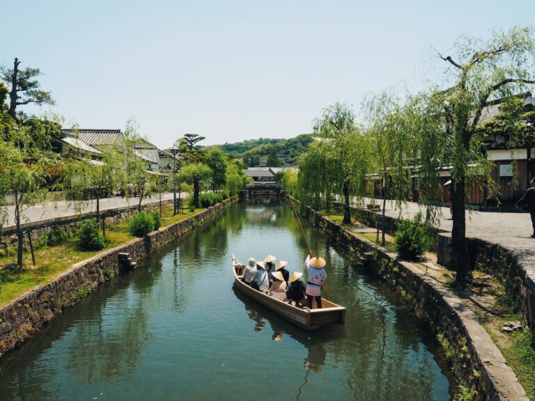 A traditional boat carrying visitors along the willow-lined canal in the Kurashiki Bikan Historical Quarter