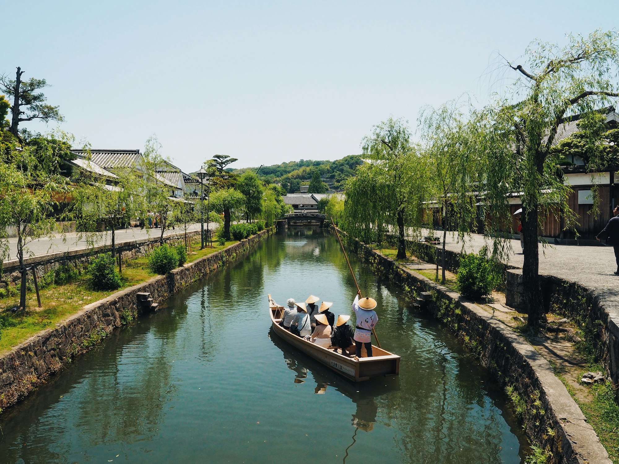 A traditional boat carrying visitors along the willow-lined canal in the Kurashiki Bikan Historical Quarter