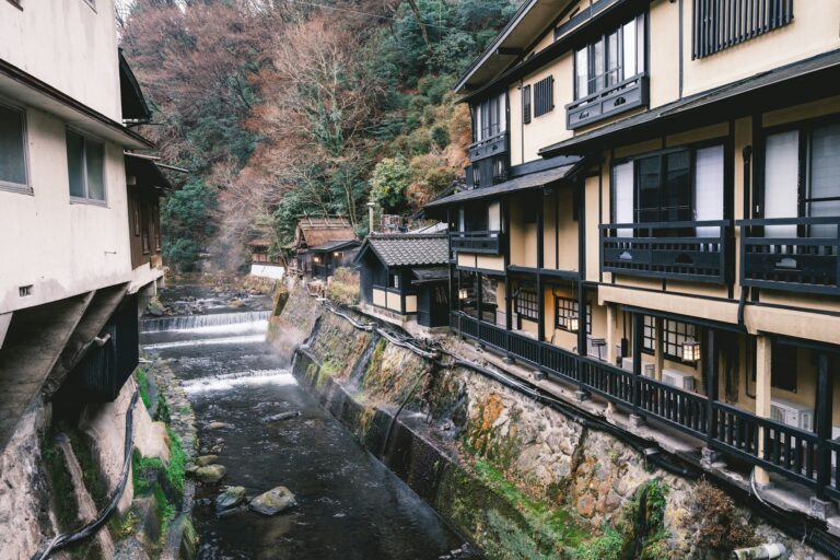 Wooden ryokan buildings along the stream in Kurokawa Onsen