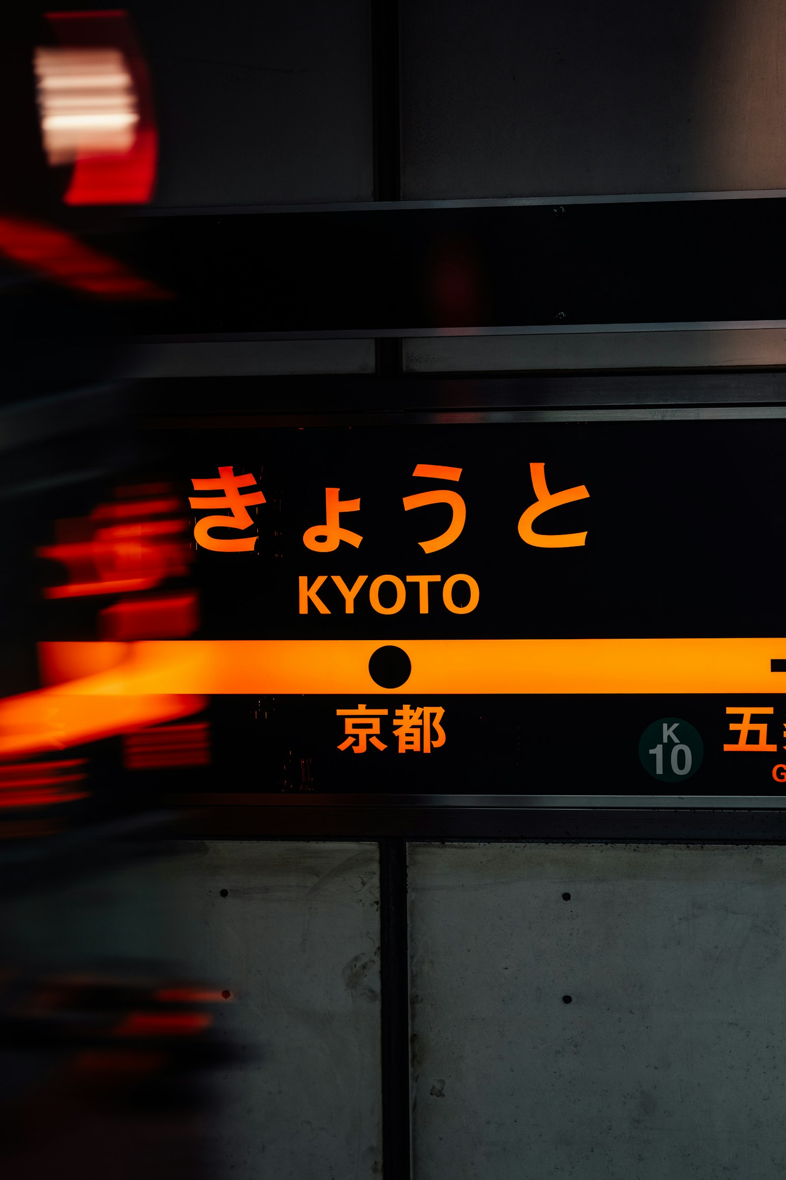 Kyoto Station sign in Japanese and English with a train passing