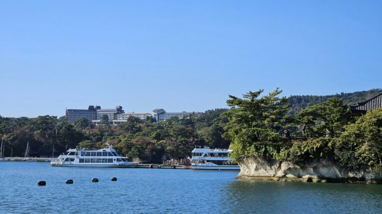 Sightseeing boats on Matsushima Bay beside a pine-covered rock island