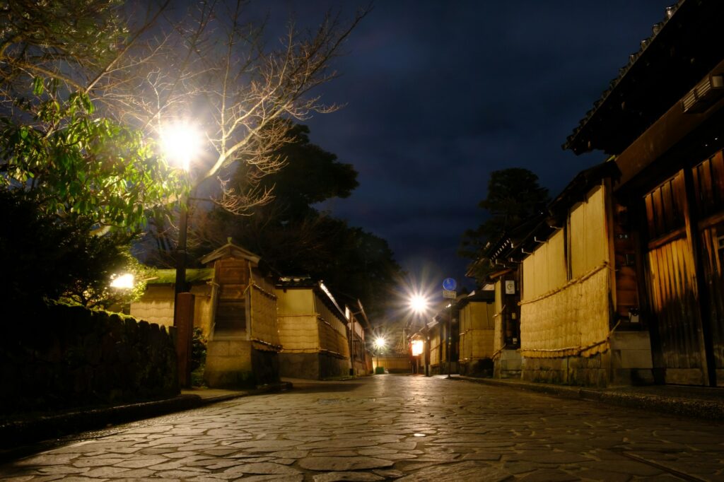Earthen walls and a lamp-lit lane in the Nagamachi samurai district at night