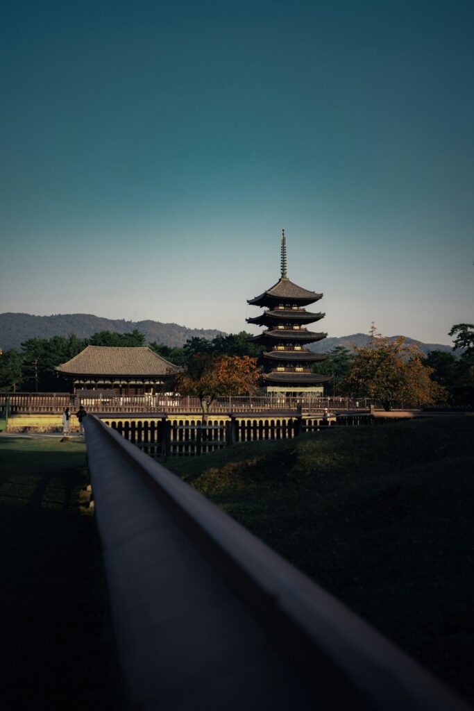 A five-story wooden pagoda and temple hall in Nara at golden hour