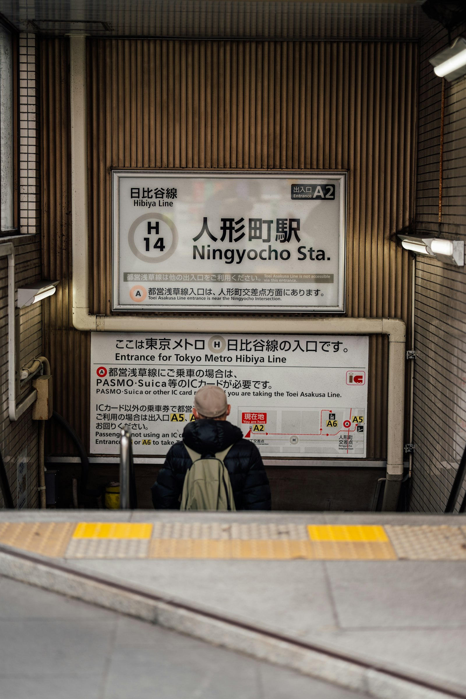 Ningyocho Station sign with the Hibiya Line H14 station number on a Tokyo subway platform