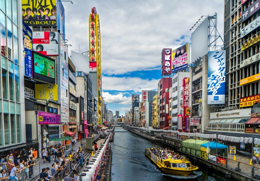 Sightseeing boat on the Dotonbori canal lined with signs in Osaka