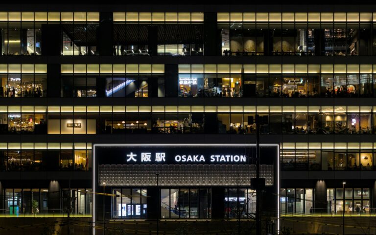 Osaka Station sign in English and Japanese in front of the lit-up station building at night