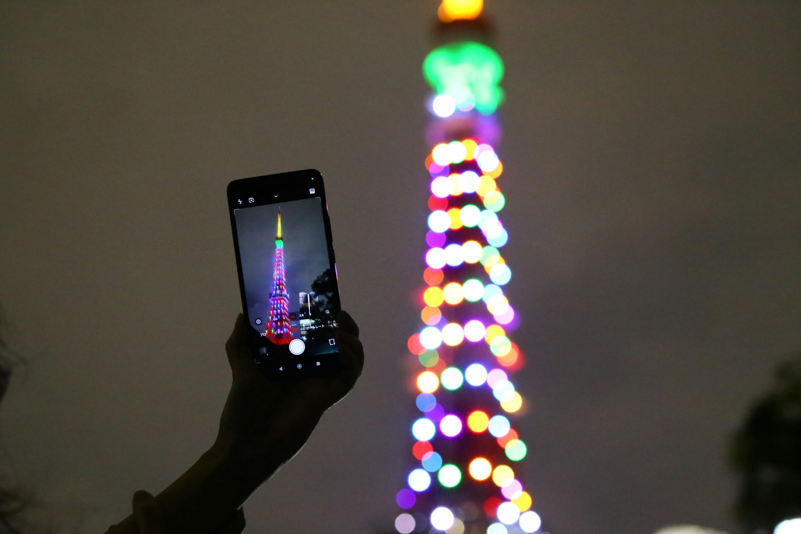 A traveler photographs Tokyo Tower at night. Maps, translation and photo backups all lean on mobile data in Japan.