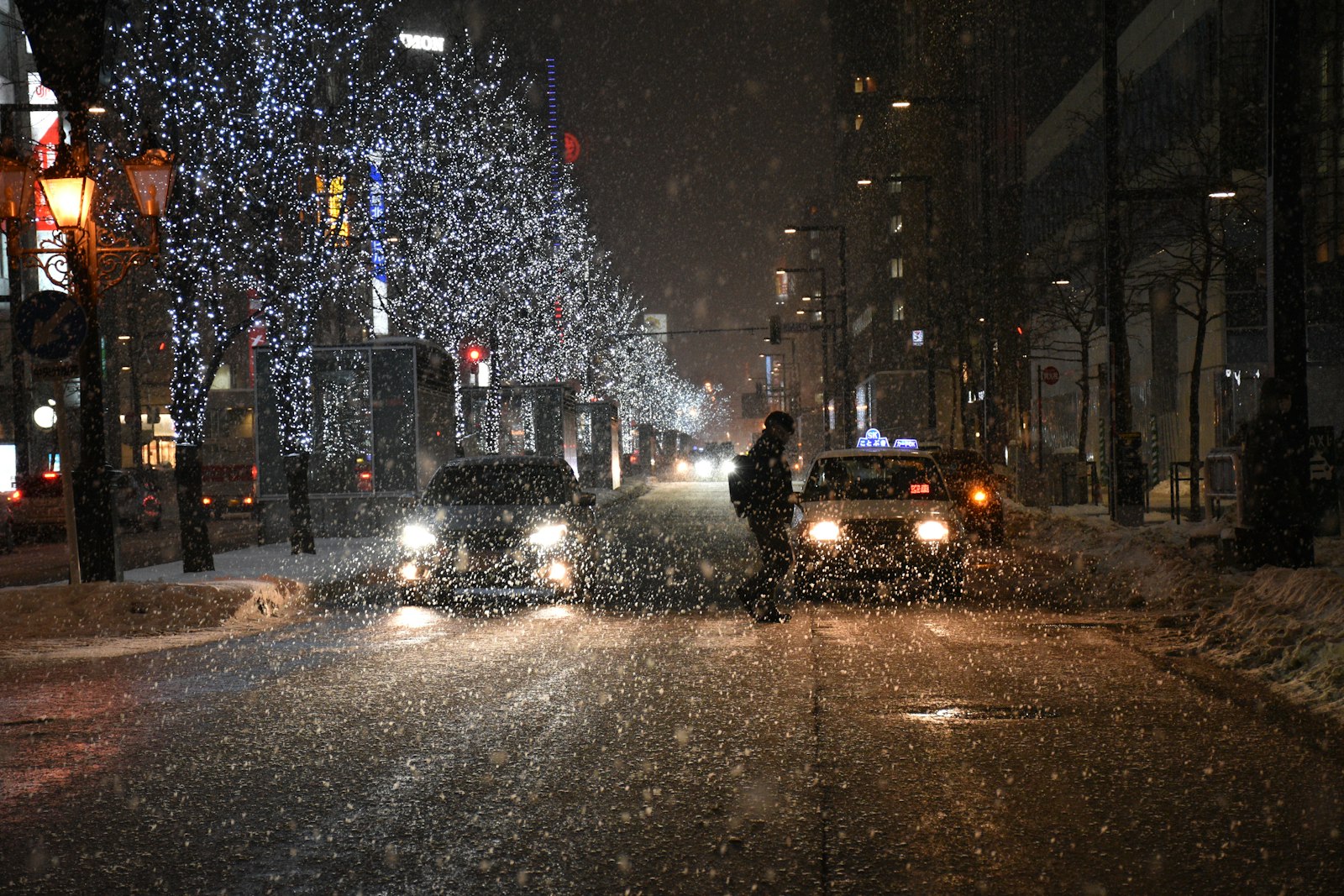 Cars driving on a snowy street in Sapporo at night