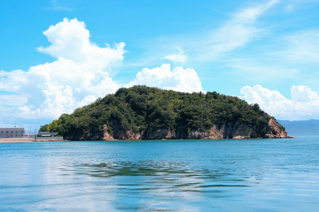 A small wooded island in calm sunlit coastal waters in Japan